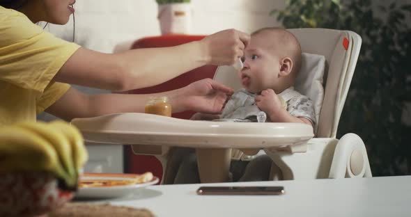 Mother Feeding Child in Kitchen