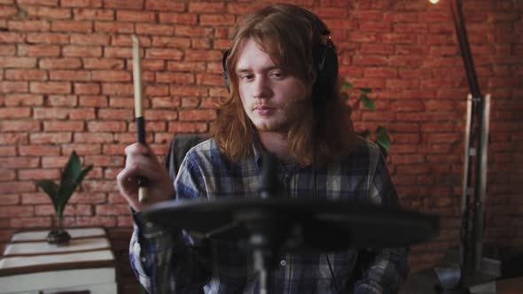 Young Redhead Man Drummer in Headphones Playing Electric Drums at Home Slow Motion Close Up