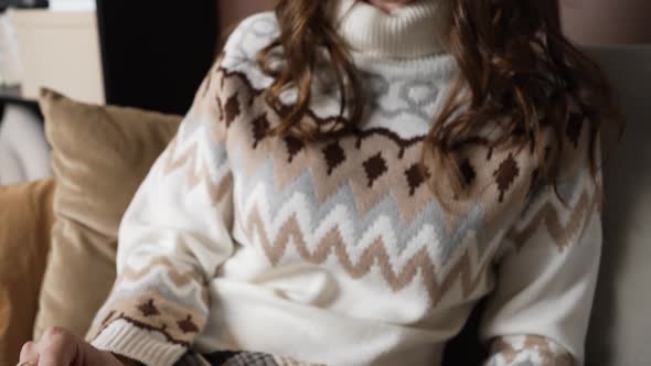 Woman Covered with Blanket Sits on Sofa and Reads Book