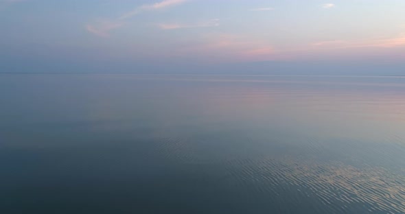 Flying Backwards Over Calm Sea at Sunset