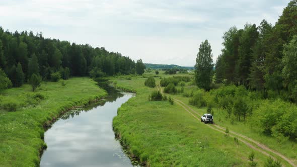 Aerial View of a Car Driving Along the River Bank