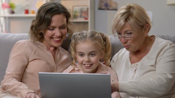 Little Girl Showing Funny Video on Laptop to Mom and Granny, Humorous Show