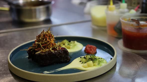 The Chef Serves a Piece of Meat on a Plate and Pours It with Sauce