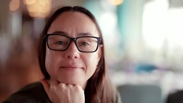 Pretty Middleaged Woman with Glasses for Correcting Vision is Looking at Camera