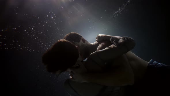 A Man Passionately Embraces and Touches His Woman Underwater Lovers Deep Inside on a Dark Background