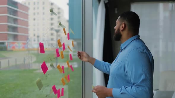 Focused Bearded Man Changing Business Plan Written on Window