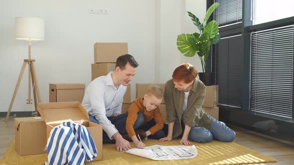 Happy Young Family Looking at Blueprint Planning New Home Interior Design Settling in Homeowners