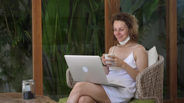 Young Woman in Protective Mask Enjoying Video Call on Terrace with Palms
