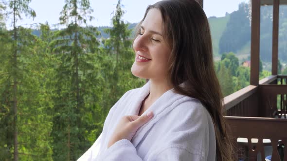 Portrait of Smiling Woman in Bathrobe Enjoying View on Mountains From Her Hotel Room