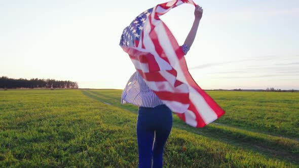 Young Woman Runs with an USA Flag Across a Field at Sunset Slow Mo