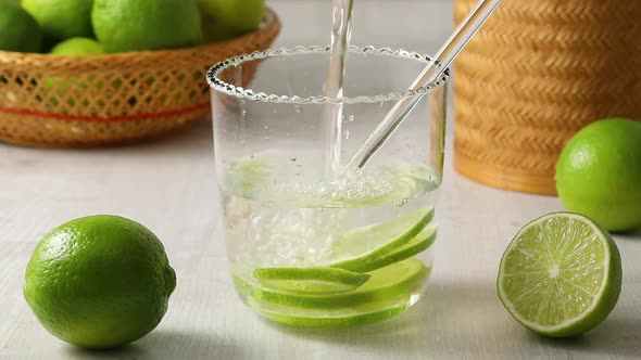 Fresh green limes and glass of water with lime slices as a healthy drink 