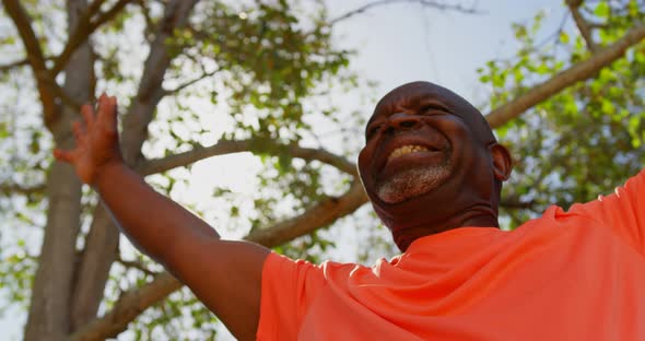 Low angle view of active African American senior man performing yoga in the garden of nursing home 4