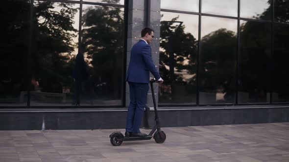 Young Businessman Riding an Electric Scooter for a Business Meeting in the Office Office Buildings