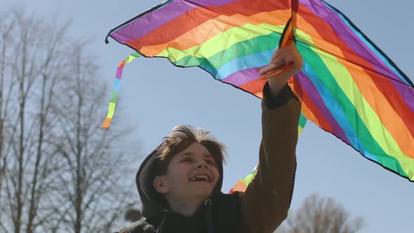 A Happy Boy is Playing with a Flying Rainbow Kite