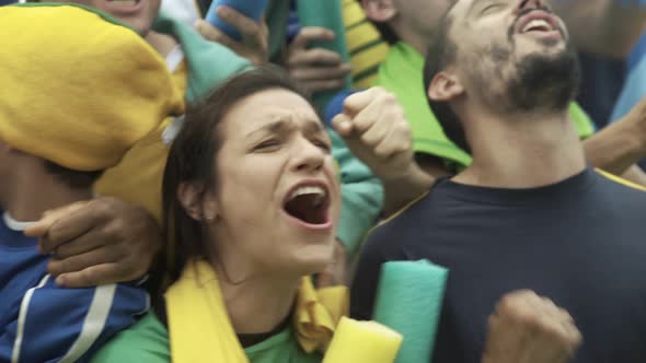 Brazilian soccer fans watching match at stadium and cheering excitedly