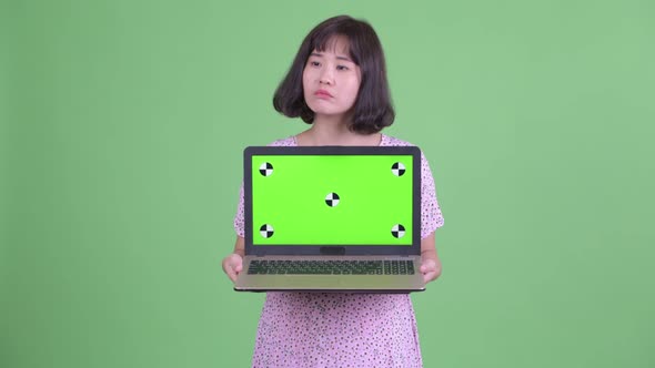 Happy Asian Pregnant Woman Thinking While Showing Laptop