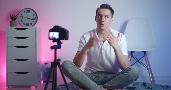 Portrait of Male Videoblogger Filming New Vlog Video with Professional Camera While Sitting on Floor