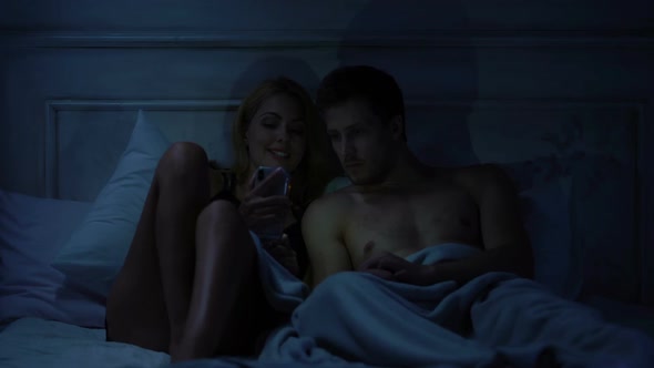 Male and Lady in Bed Looking Old Photos on Smartphone Together, Application