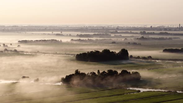 Early morning golden hour light and mist over vast Dutch farm lands; aerial