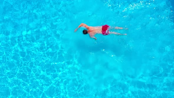 View From the Top As a Man in Red Shorts Swims in the Pool