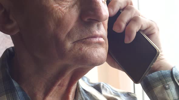 Portrait of a serious caucasian man 70 years old attentively listening to a caller on the phone. Tho