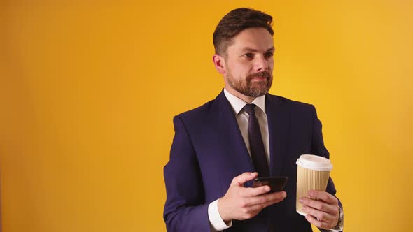 Attractive Caucasian Businessman with Cellphone and Coffe - Isolated on Yellow Background