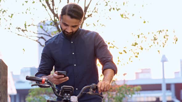 Indian Man Using Phone Using Bike Rental App Renting Bicycle in City Park