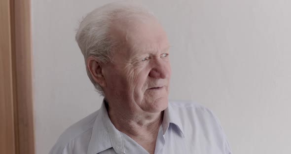 Healthy Older Man Looking Out the Window and Smiling at Camera During Isolation