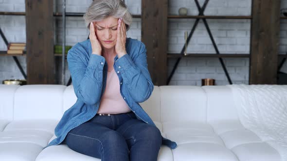 Older Woman Sit on Sofa Coping with Headache 