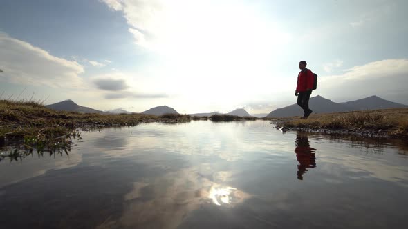 Hiker Walking Close To Sunlit Pond In Klakkur