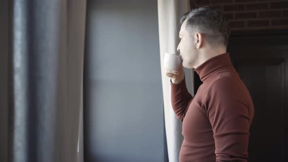 Side View of Confident Successful Man Drinking Coffee and Looking Out the Window