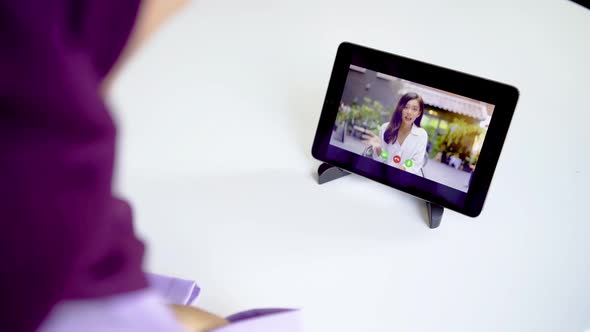 Young muslim woman sitting at a table in the room negotiate using tablet and video call app