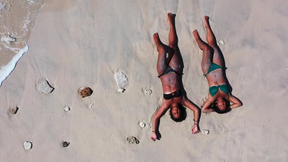 Young smiling girls on photoshoot in the sun at the beach on paradise white sand and blue background