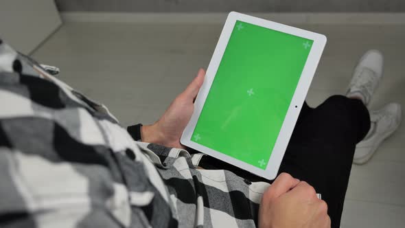 Man Sitting on Chair Looking at Digital Tablet with Green Screen Chroma Key