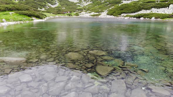 AERIAL: Flying Backwards Low over Crystal Clear Mountain Lake in Slovakia