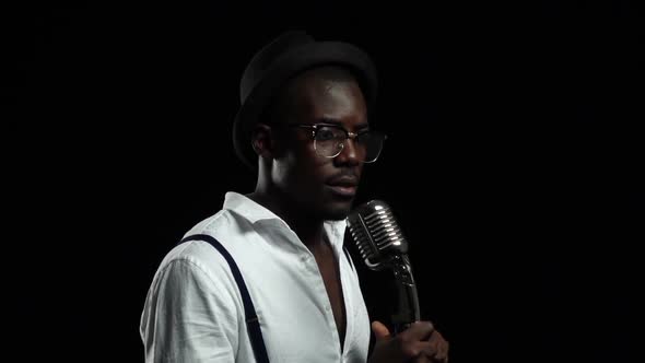 Singer Holding His Microphone and Gesticulating Hands Sings. Black Background. Slow Motion. Close Up