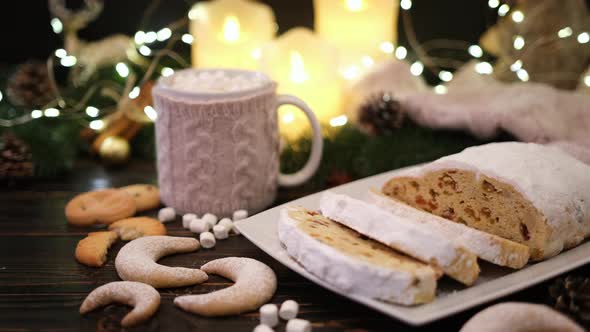 Sliced Traditional Christmas Stollen Cake with Marzipan and New Year Decorations on Wooden