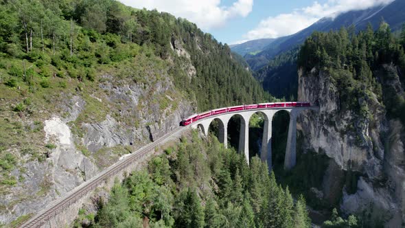 Aerial View of a Moving Red Train Along the Landwasser Viaduct in Swiss Alps