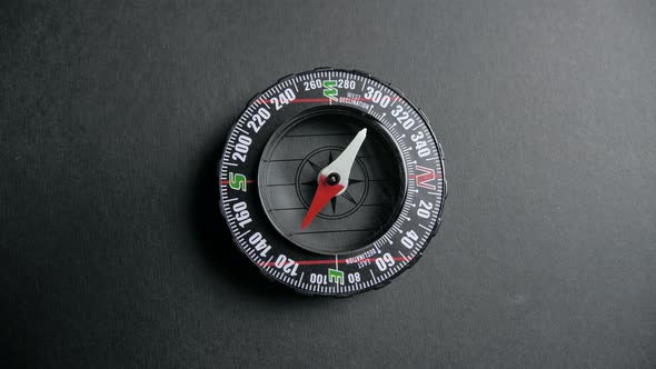 a Modern Compass Lying on a Black Desk with a Red Arrow That Shows the Direction. Concept of Travel