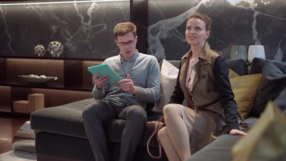 Portrait of Positive Confident Successful Couple Sitting on Soft Couch Leaning Talking and Smiling