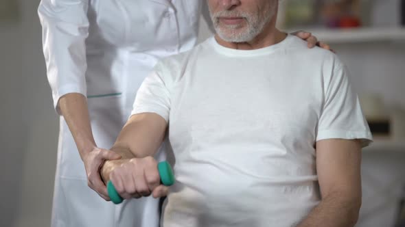 Nurse Helping Pensioner to Lift Dumbbell, Rehabilitation Center After Insult