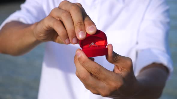 Male Hands With Wedding Ring. Romantic Marriage Proposal On The Beach.