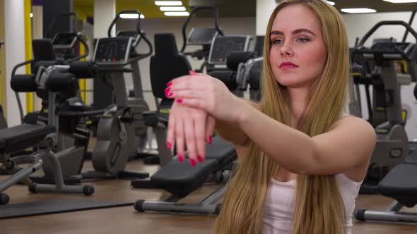 A Young Beautiful Woman Stretches Her Hands in a Gym - Closeup