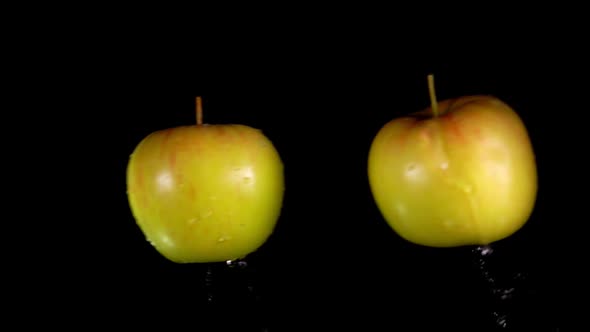 Two Yellow Apples Are Flying To Each Other and Colliding on the Black Background