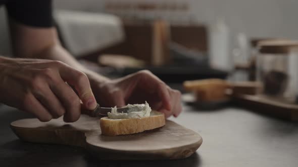 Slow Motion Man Spread Cream Cheese Over Ciabatta Slice on Olive Board