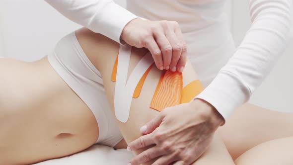 Therapist is applying kinesio tape to female body. Physiotherapy, kinesiology and recovery.