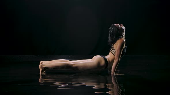 Athletic Young Woman Practicing Upward Downward Dog Yoga Position. Shot in a Dark Studio