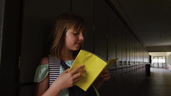 Girl reading books in the school corridor