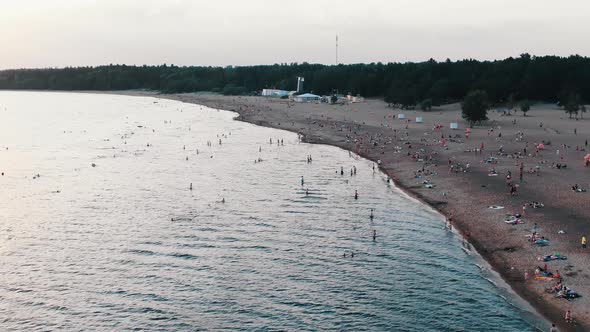 Long Sand Beach at Seaside and People Swim and Sunbathe