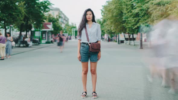 Time-lapse of Asian Lady Standing in City on Pedestrian Street Looking at Camera